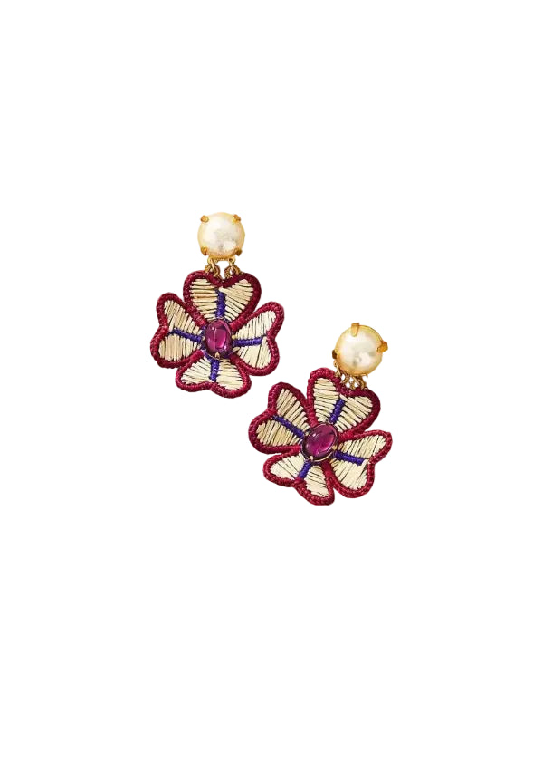 Floral earrings with purple gemstones and pearl-like centers on a beige background