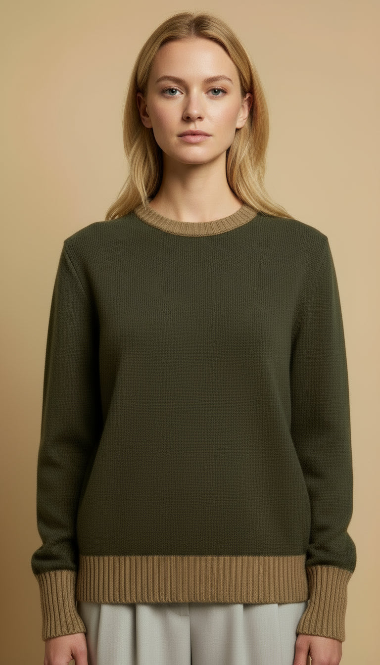 Woman wearing a green sweater over a brown shirt with white pants.