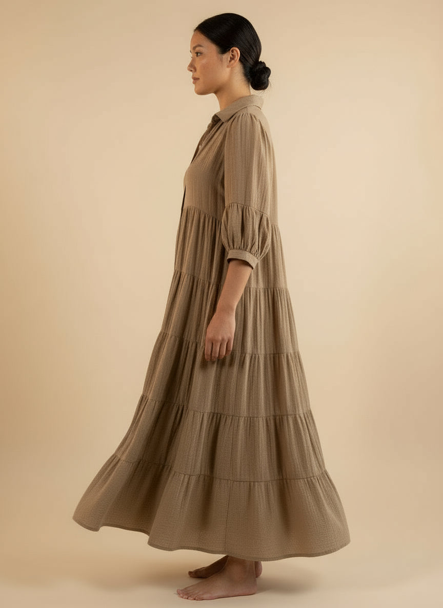 Woman wearing a long, tiered brown dress.