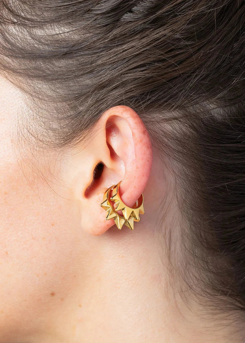 Gold star-shaped earring worn by a person with gray hair.