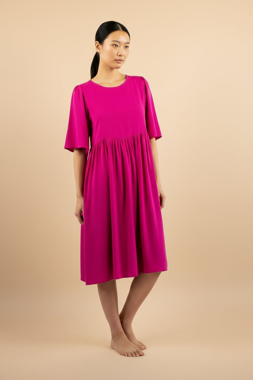 Woman wearing a bright pink dress against a beige background